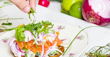 red onions, carrots, radishes, and chives being stacked on a plate