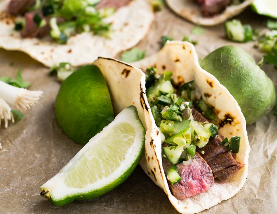 Close up view of carne asada taco with lime wedges