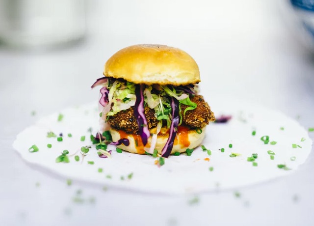 Side view of 'green' burger with onions and choves on a plate